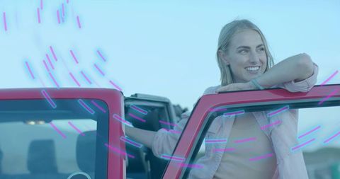 Smiling Woman Leaning on Red Convertible in Open Field, Joyful Adventure Vibe