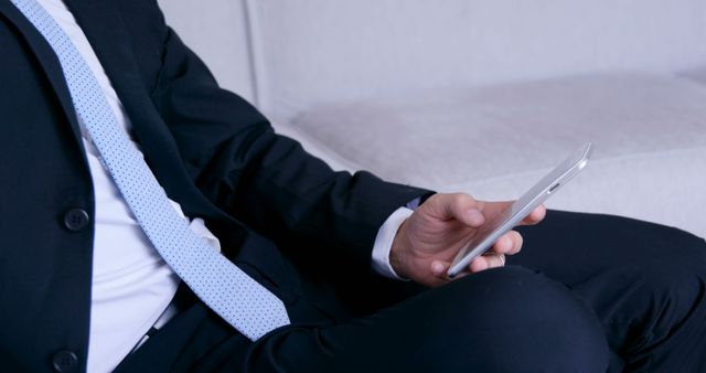 Hand of caucasian man in suit using smartphone on couch at home, copy space. Lifestyle, domestic life, business and work, communication, unaltered.