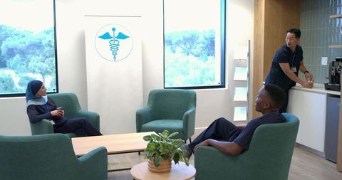 Multicultural healthcare staff taking coffee break in bright modern staff lounge
