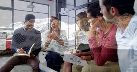 Diverse team collaborating in modern office brainstorming with data overlay and handouts