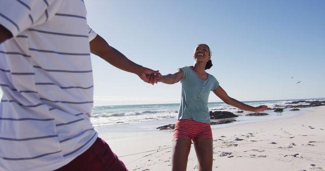 African american couple smiling, holding hands and running on the beach. healthy outdoor leisure time by the sea.