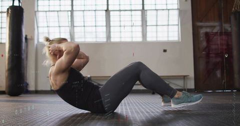 Woman doing crunches in bright gym studio for core workout and functional fitness training