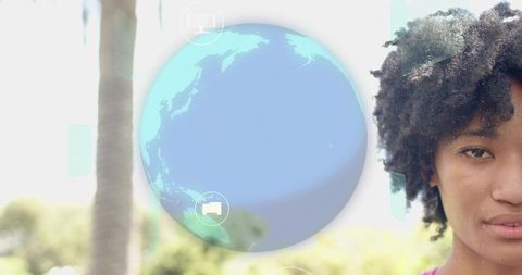 Woman with curly hair viewing augmented reality globe with floating ui icons outdoors