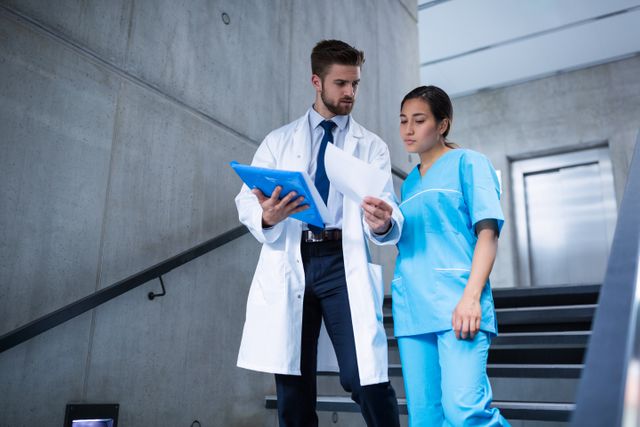 Doctor and nurse discussing over a report while climbing down stairs in hospital