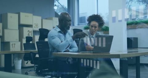 Diverse team evaluating data trends on laptop in modern office