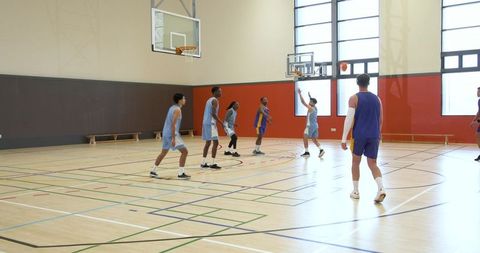 Basketball players in action on indoor court with shot attempt