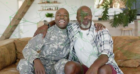Smiling soldier hugging father on couch celebrating homecoming and family reunion joy