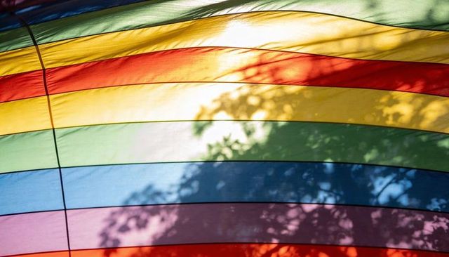 Glowing rainbow fabric panels casting leaf shadows through translucent striped canopy