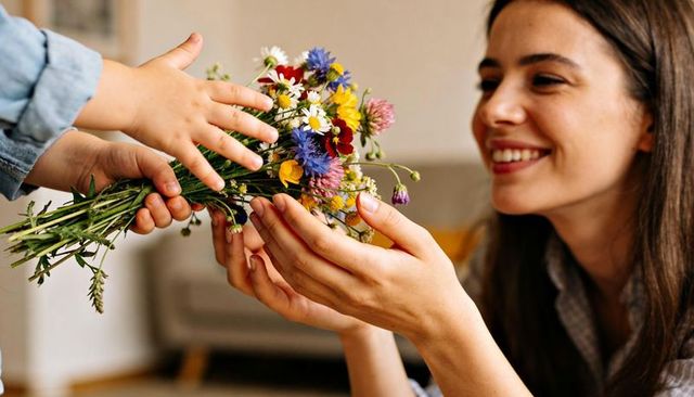 Smiling woman receiving wildflower bouquet from child, warm home gift moment affectionate closeup