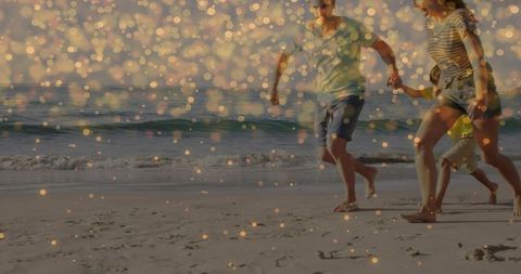Family sprinting barefoot along sunlit beach with golden bokeh, footprints and sunset glow