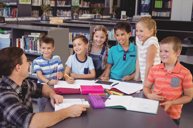 Happy schoolkids interacting with teacher in library at school