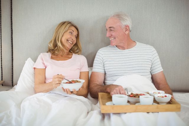 Smiling couple having breakfast on bed in bed room