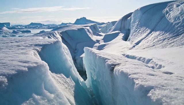 Blue-glazed crevasse cutting through polar glacier with dramatic sunlit ice ridges