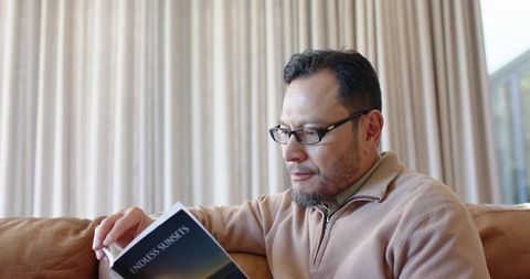 Mature Asian Man Reading Book at Home for Relaxation