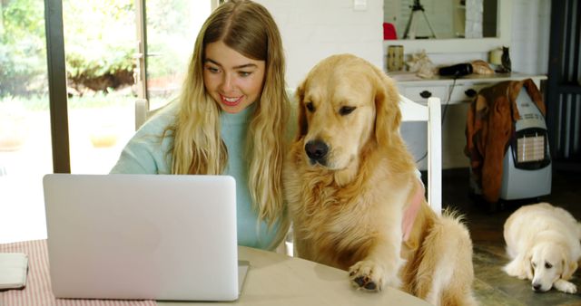 Woman sitting with Golden Retriever while using laptop in home environment. Perfect for illustrating remote work, pet-friendly workspaces, home office setups, or the bond between humans and their pets. Great for blogs about working from home, pet care, or productivity tips.