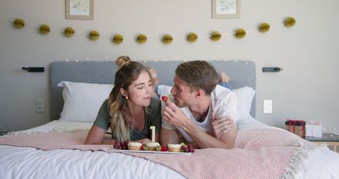 Couple Sharing Grapes Relaxing Together at Home on Bed