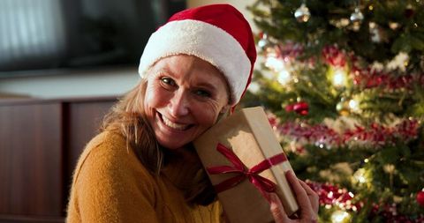 Senior Woman with Christmas Gift by Decorated Tree
