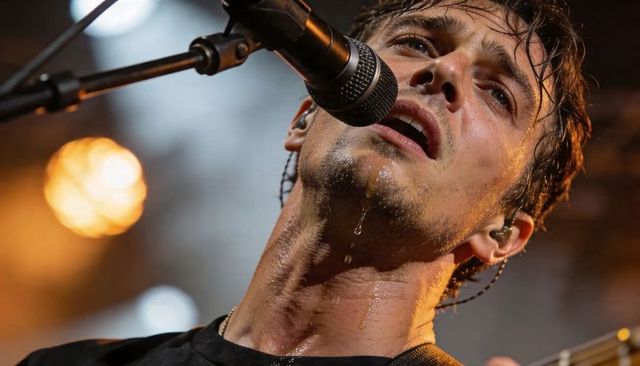 Close-up male singer leaning into microphone singing sweat and emotion at live concert