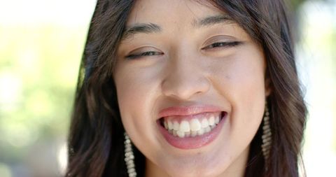 African american woman smiling broadly wearing beaded earrings closeup outdoors
