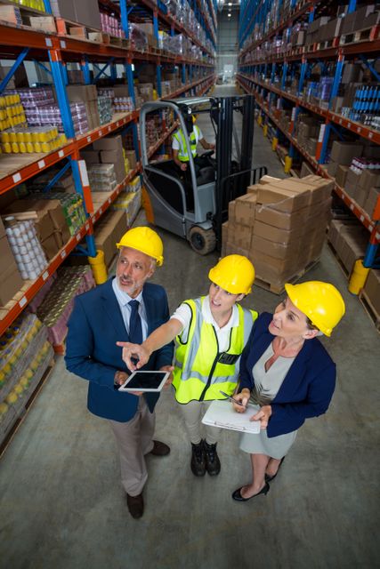 Warehouse manager interacting with client and female worker in warehouse