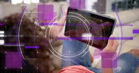 Curly-haired man using tablet on couch showing futuristic hud overlay for home media tech