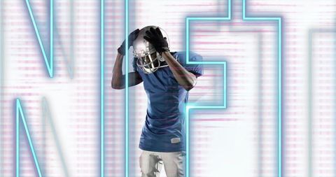 Football player adjusting helmet in neon cyan studio with futuristic lettering