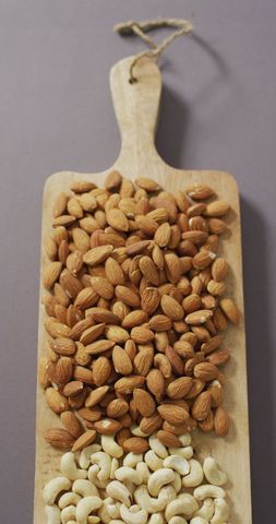 Nut selection on wooden board with lilac background