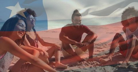 Laughing friends enjoying summer beach day, sitting on sand, chatting and holding bottle