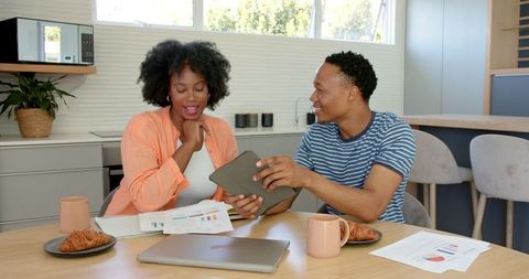 African american couple managing finances in modern kitchen with tablet