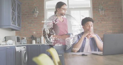Couple working from home in modern kitchen with digital globe and data overlay