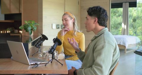 Diverse Co-Hosts Recording Podcast with Laptop and Microphones in Minimalist Home Studio