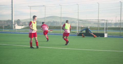 Field hockey game action with diving goalkeeper and team