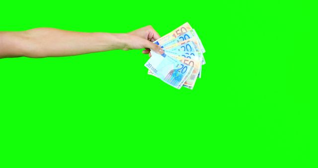 A Caucasian hand is holding a fan of Euro banknotes against a bright green background, with copy space. Offering cash in this manner can suggest themes of financial transactions, rewards, or incentives.