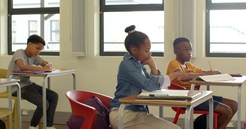 Diverse Students Writing in Bright Classroom Setting