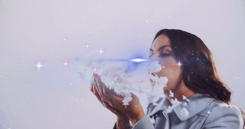 Woman blowing sparkling cloud vapor creating magical light trail and starry glow