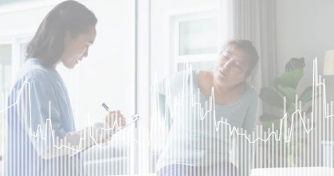 Home healthcare consultation with clinician taking notes and patient reporting back pain