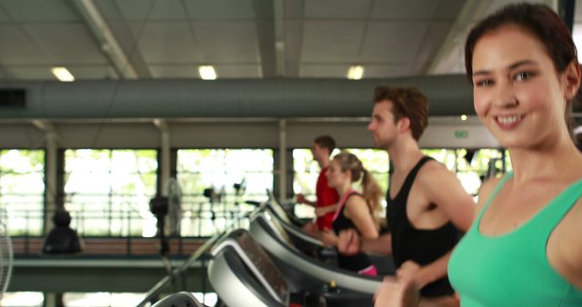 A group of people running on treadmills in a modern gym. They appear energetic and focused. The scene reflects health, fitness, and dedication to a healthy lifestyle. The background shows a well-equipped interior, emphasizing cleanliness and modernity. Perfect for promoting fitness centers, gym membership advertisements, fitness motivation campaigns, and articles related to health and wellness.