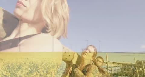 Women Carrying Log in Fields with Wind Turbines in Background