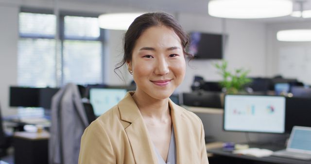 Businesswoman smiling in modern office, exuding confidence and professionalism. Ideal for corporate, business, and technology-related projects showcasing professional environments and successful women in business.