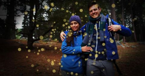 Couple hiking and embracing under pine trees with golden bokeh light particles
