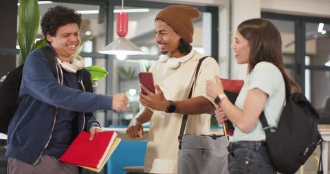 African american students sharing smartphone and laughing with classmates in modern coworking lounge
