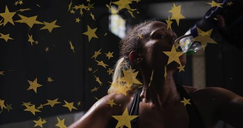 Sweaty athlete sipping water between sets under studio lights with gold star overlay
