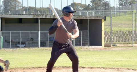 Male batter preparing to swing on baseball field wearing helmet and compression sleeve