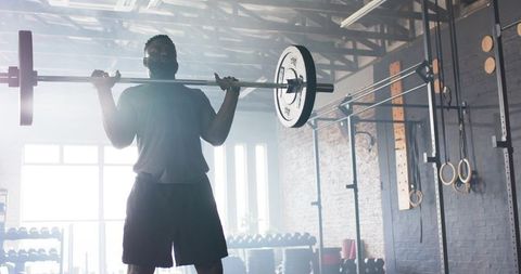 Dedicated athlete training with barbell in industrial gym setting