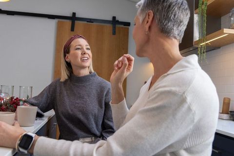 Cozy rustic kitchen morning conversation with younger woman and senior man sharing coffee