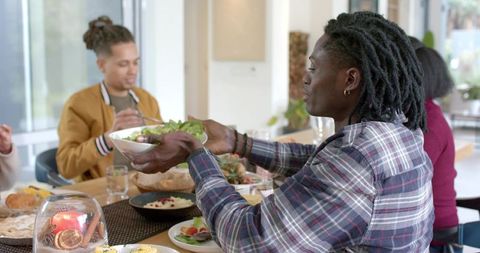Friends Sharing Salad at Long Wooden Table in Bright Contemporary Dining Space