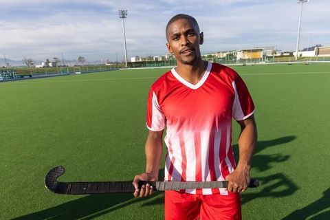 Confident african american field hockey player posed on green turf