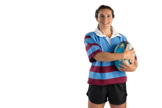 This image features a happy female rugby player holding a rugby ball against a white background. Ideal for use in sports promotions, advertisements for women's sportswear, fitness campaigns, and articles about women's participation in sports. The image conveys confidence, strength, and enthusiasm for the sport.