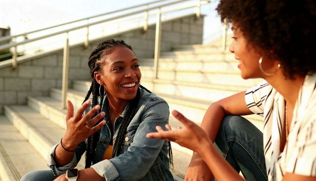 Urban steps conversation at golden hour — young women laughing, talking and gesturing