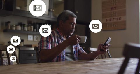 Senior Man Engaged with Email Notifications in Kitchen